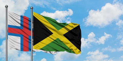 Faroe Islands and Jamaica flag waving in the wind against white cloudy blue sky together. Diplomacy concept, international relations.