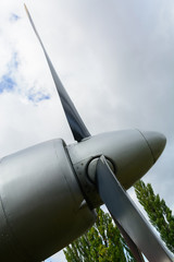 Part of the fuselage of the old military plane with the propeller closeup against the background of an empty and gray sky.