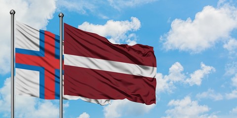Faroe Islands and Latvia flag waving in the wind against white cloudy blue sky together. Diplomacy concept, international relations.