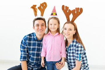 Winter holidays concept - Christmas family wearing Santa Hat and deer horns. Smiling Family Celebration