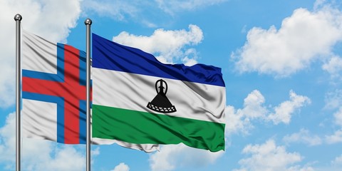 Faroe Islands and Lesotho flag waving in the wind against white cloudy blue sky together. Diplomacy...