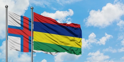 Faroe Islands and Mauritius flag waving in the wind against white cloudy blue sky together. Diplomacy concept, international relations.