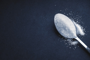 Minimalist flat lay composition sugar and spoon on the dark background. Medical, Healthcare and...