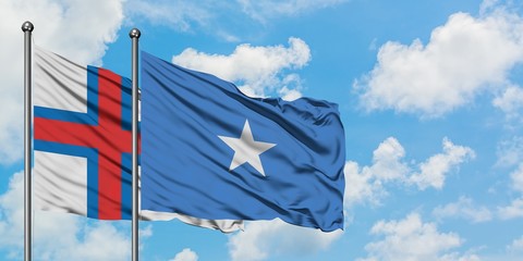 Faroe Islands and Somalia flag waving in the wind against white cloudy blue sky together. Diplomacy...