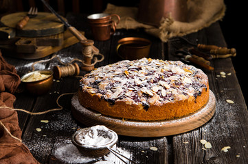 homemade tasty biscuit cake with cherries, almond flakes, powdered sugar on top