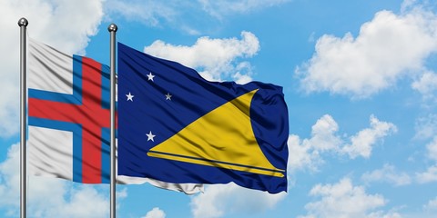 Faroe Islands and Tokelau flag waving in the wind against white cloudy blue sky together. Diplomacy...