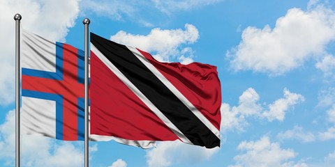 Faroe Islands and Trinidad And Tobago flag waving in the wind against white cloudy blue sky together. Diplomacy concept, international relations.