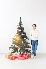 holidays and winter childhood concept - smiling teen boy standing near christmas tree on white background