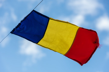 Romanian flag on flagpole blowing in wind isolated on blue sky