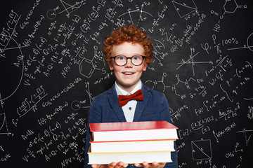 Clever kid boy in glasses holding book, portrait