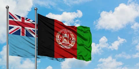Fiji and Afghanistan flag waving in the wind against white cloudy blue sky together. Diplomacy...
