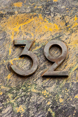 antique brass number 32 on yellow stone wall