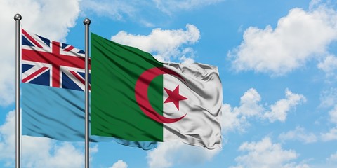 Fiji and Algeria flag waving in the wind against white cloudy blue sky together. Diplomacy concept,...