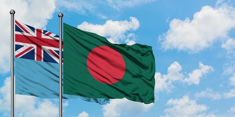 Fiji and Bangladesh flag waving in the wind against white cloudy blue sky together. Diplomacy...