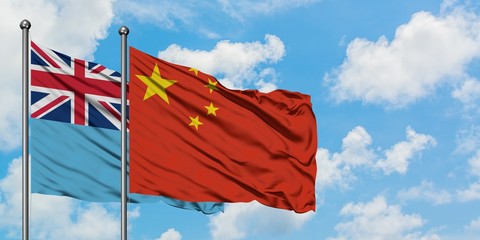 Fiji and China flag waving in the wind against white cloudy blue sky together. Diplomacy concept, international relations.