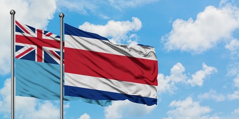 Fiji and Costa Rica flag waving in the wind against white cloudy blue sky together. Diplomacy concept, international relations.