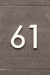 brass number 61 on stone wall