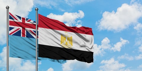 Fiji and Egypt flag waving in the wind against white cloudy blue sky together. Diplomacy concept, international relations.