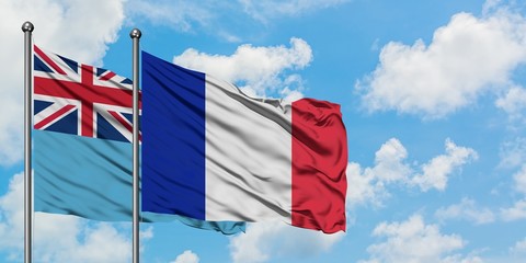 Fiji and France flag waving in the wind against white cloudy blue sky together. Diplomacy concept,...