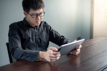 Young Asian businessman using digital tablet in office meeting room. Male entrepreneur reading news on social media app. Online marketing and Big data technology for E-commerce business.