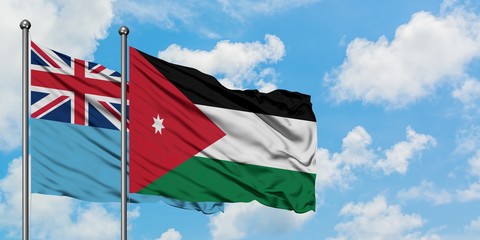Fiji and Jordan flag waving in the wind against white cloudy blue sky together. Diplomacy concept, international relations.
