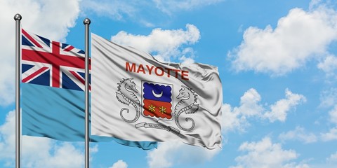 Fiji and Mayotte flag waving in the wind against white cloudy blue sky together. Diplomacy concept, international relations.