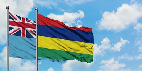 Fiji and Mauritius flag waving in the wind against white cloudy blue sky together. Diplomacy concept, international relations.