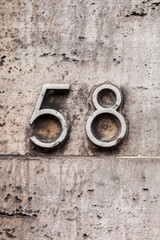 tarnished number 58 on white stone wall