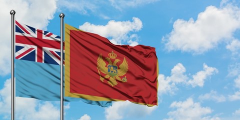 Fiji and Montenegro flag waving in the wind against white cloudy blue sky together. Diplomacy concept, international relations.