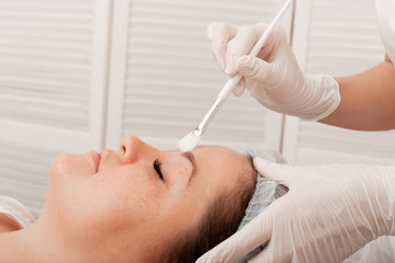 Hand of a cosmetologist doctor in a white glove, touches a woman's face. Cosmetology, beauty clinic