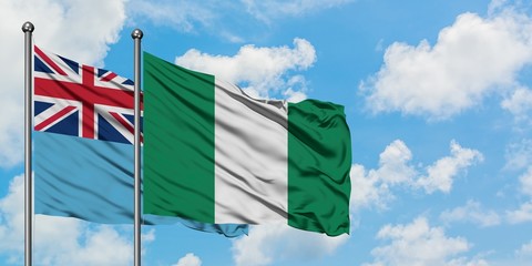 Fiji and Nigeria flag waving in the wind against white cloudy blue sky together. Diplomacy concept, international relations.