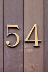 brass number 54 on stone wall