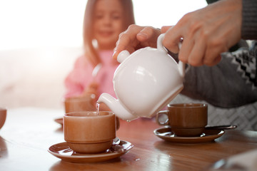 A man pours tea for his daughter