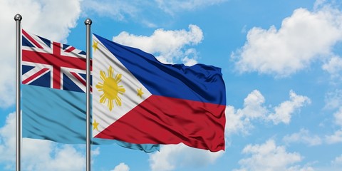 Fiji and Philippines flag waving in the wind against white cloudy blue sky together. Diplomacy concept, international relations.