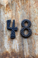 antique black metal number 48 on granite wall