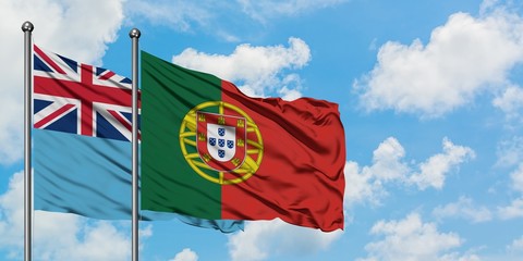 Fiji and Portugal flag waving in the wind against white cloudy blue sky together. Diplomacy concept, international relations.