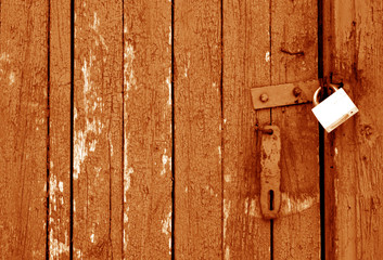 Grungy wooden door with lock in orange tone.