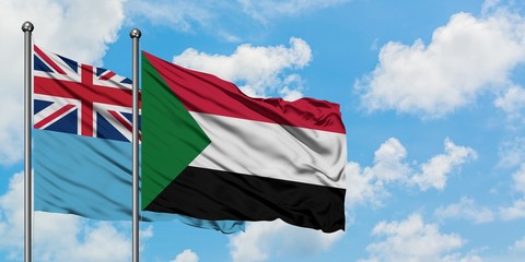 Fiji and Sudan flag waving in the wind against white cloudy blue sky together. Diplomacy concept, international relations.