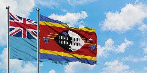 Fiji and Swaziland flag waving in the wind against white cloudy blue sky together. Diplomacy concept, international relations.