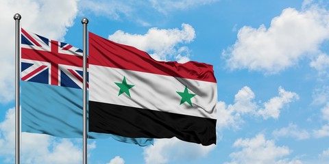 Fiji and Syria flag waving in the wind against white cloudy blue sky together. Diplomacy concept, international relations.