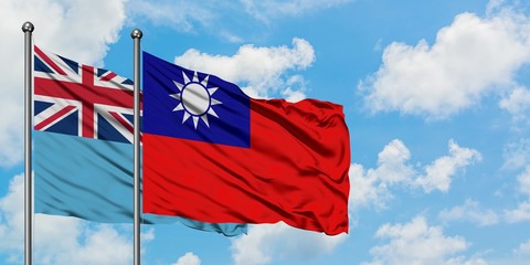 Fiji and Taiwan flag waving in the wind against white cloudy blue sky together. Diplomacy concept, international relations.