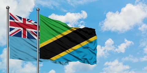 Fiji and Tanzania flag waving in the wind against white cloudy blue sky together. Diplomacy concept, international relations.