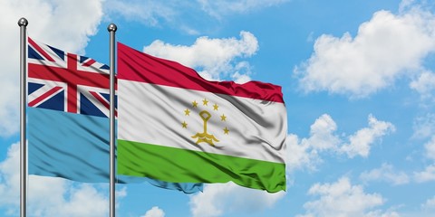 Fiji and Tajikistan flag waving in the wind against white cloudy blue sky together. Diplomacy concept, international relations.
