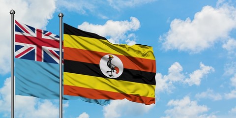 Fiji and Uganda flag waving in the wind against white cloudy blue sky together. Diplomacy concept, international relations.