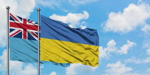 Fiji and Ukraine flag waving in the wind against white cloudy blue sky together. Diplomacy concept,...