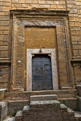 Entrance to an old church at small square in Pienza, Siena province, Tuscany, Italy