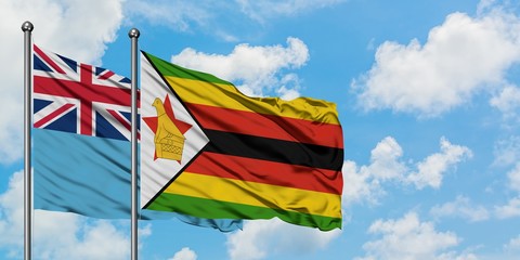 Fiji and Zimbabwe flag waving in the wind against white cloudy blue sky together. Diplomacy concept, international relations.