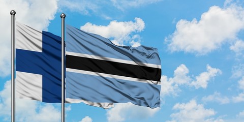 Finland and Botswana flag waving in the wind against white cloudy blue sky together. Diplomacy...