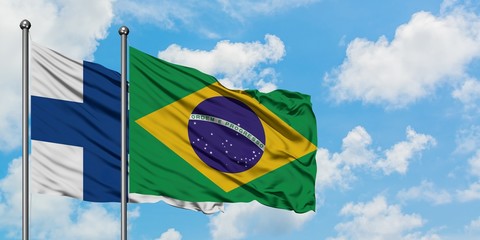 Finland and Brazil flag waving in the wind against white cloudy blue sky together. Diplomacy...