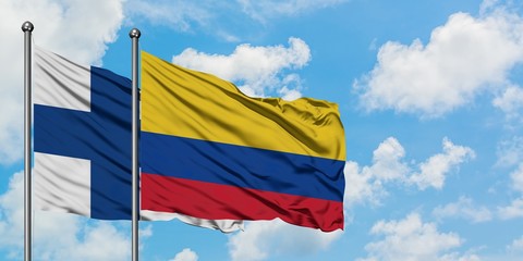 Finland and Colombia flag waving in the wind against white cloudy blue sky together. Diplomacy concept, international relations.